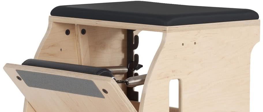 Pilates equipment with a wooden frame and black padded seat.