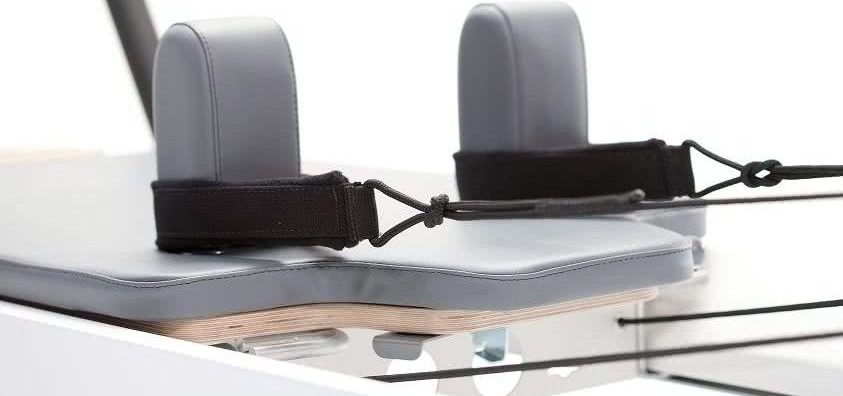 Wózek reformera Pilates z wbudowanym zagłówkiem i tapicerką w kolorze storm.