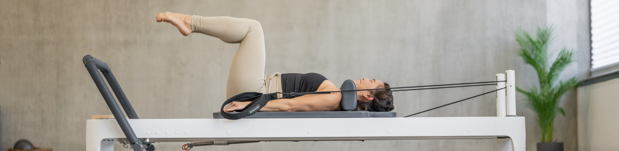 Trainer demonstrating Pilates exercise on Balanced Body reformer.