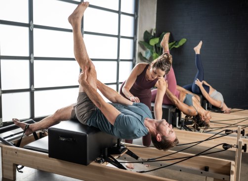 Instruktor Pilates prowadzący klienta na maszynie reformer Pilates.