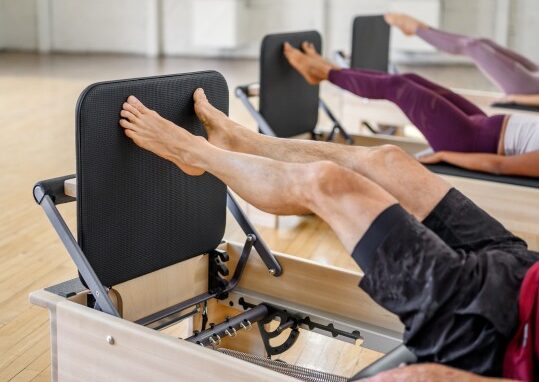 Pilates studio equipped with reformers and users exercising.