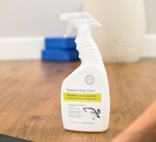 Butelka spray Balanced Body Clean na drewnianej podłodze studia.